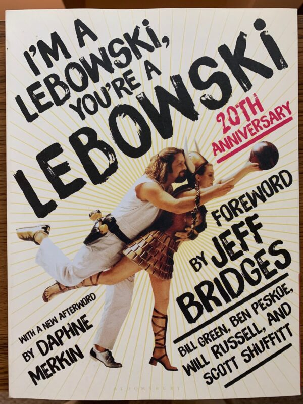 A photo of the cover of the book, I'm A Lebowski, You're A Lebowski, which features Jeff Bridges as the Dude in a loving embrace with Maude Lebowski, Julianne Moore, dressed as the Valkery.